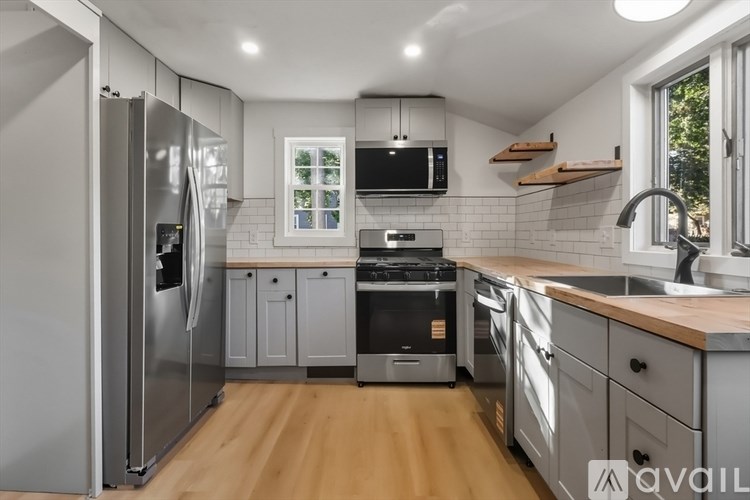 A modern kitchen with wooden floors and stainless steel appliances.