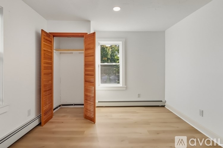 A room with a wooden floor and a window with a view of trees outside.