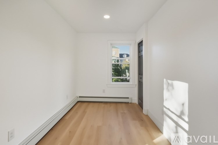A room with wooden flooring and a window showing a view of buildings outside.