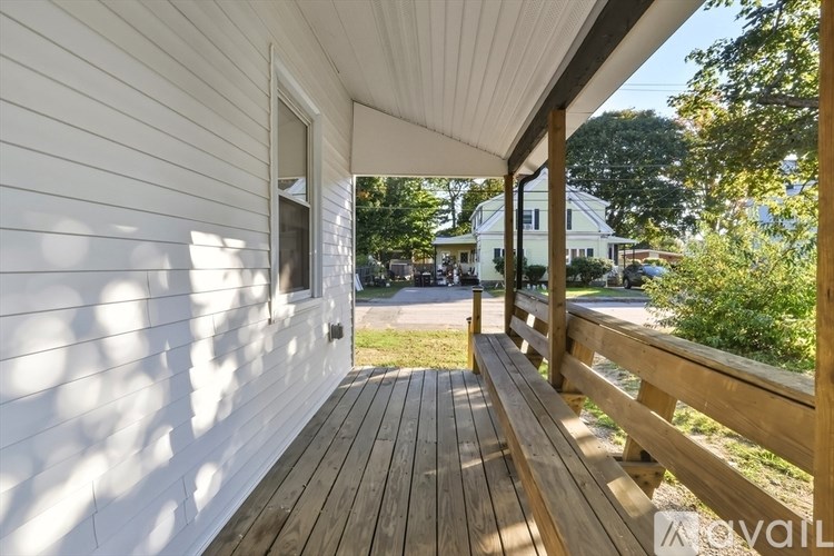 A wooden deck with a white wall and a railing.