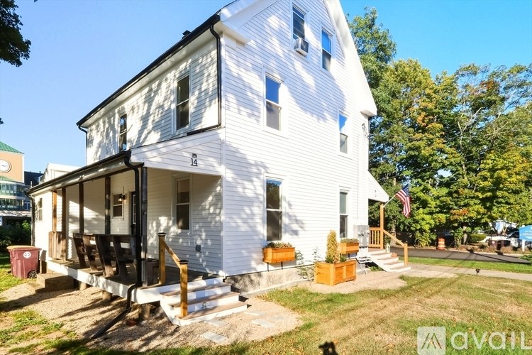 A white house with a porch and a flag on the front.
