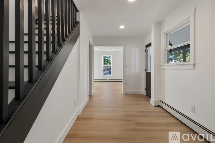 A long hallway with a wooden floor and a window on the right side.