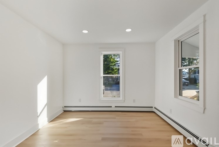 A spacious room with a large window and wooden flooring.