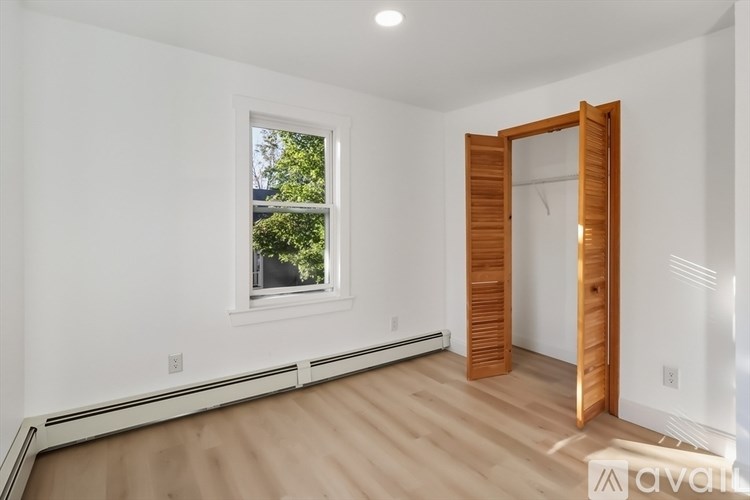 A room with a window and a wooden door is available for rent.