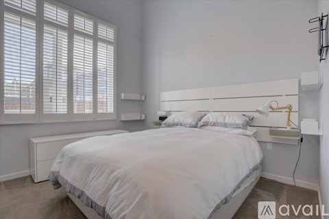 A bedroom with a large bed and a window with blinds.
