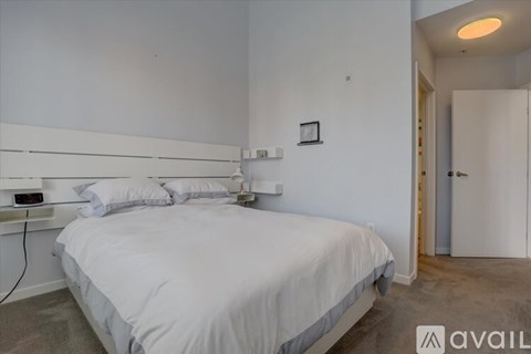 A bedroom with a bed, pillows, and a nightstand.