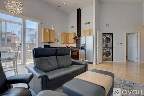 A modern living room with a grey sofa and a black leather chair.