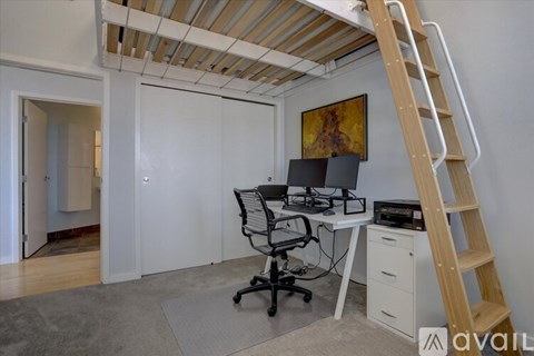 A room with a desk, chair, and a ladder.