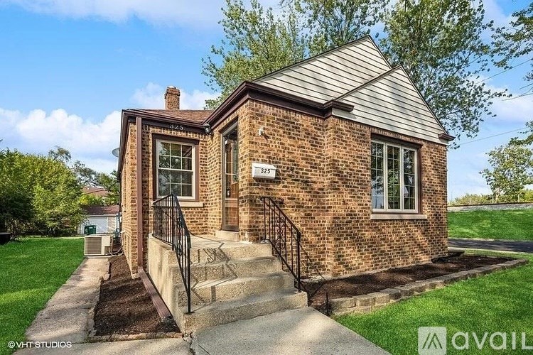 A brick house with a black iron railing on the stairs.