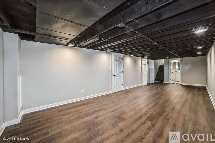 A spacious room with wooden flooring and a high ceiling.