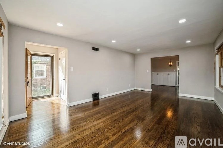 A spacious room with wood flooring and a large window.