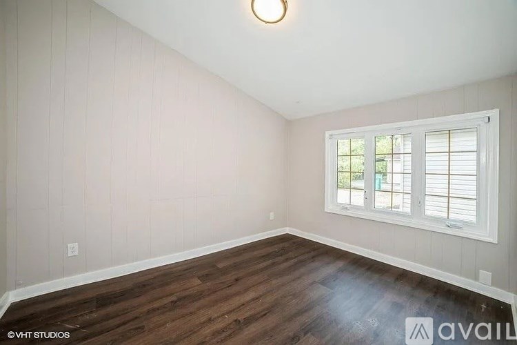 A room with wooden floors and a window with blinds.