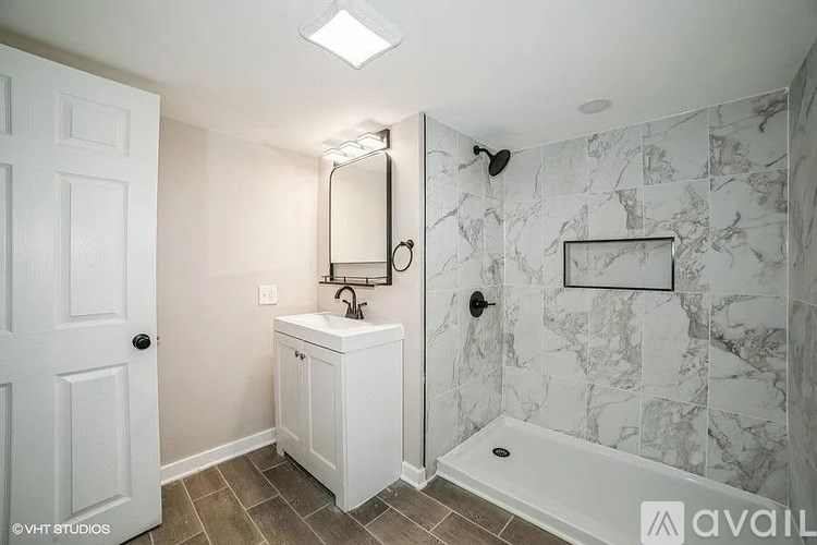 A bathroom with a marble wall and a white sink cabinet.