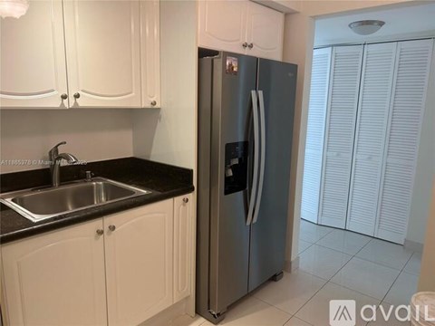 A kitchen with white cabinets and a black countertop.