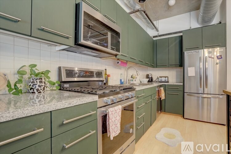 A kitchen with green cabinets and stainless steel appliances.