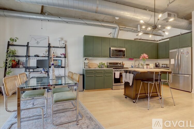A kitchen with a glass table and chairs, a refrigerator, and a dining table with a vase of flowers on it.