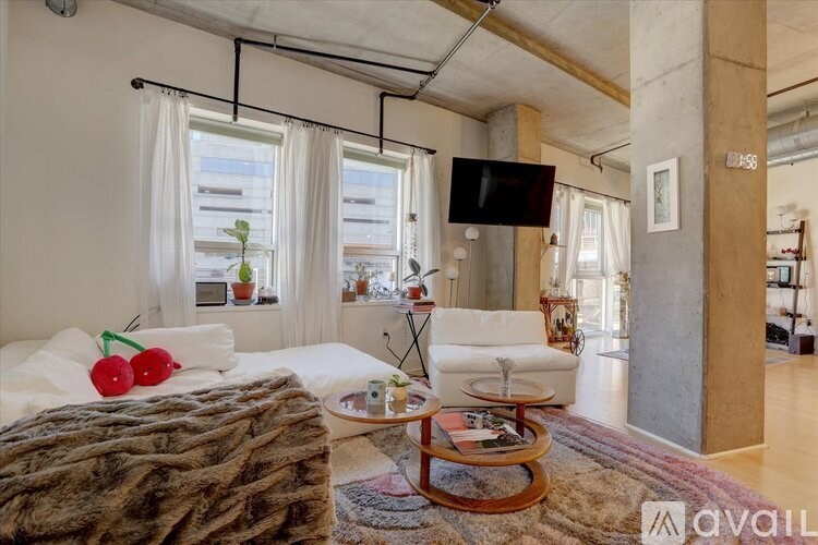 A living room with a large bed and a flat screen TV mounted on the wall.