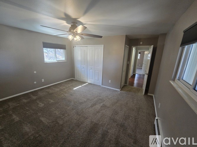 A spacious room with a ceiling fan and carpeted floor.
