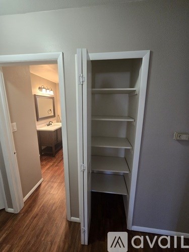 A white closet with shelves is open to a bedroom.