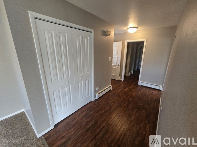 A hallway with a white door and brown flooring.