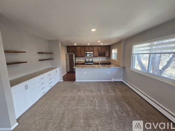 A spacious, empty room with a kitchen in the background.