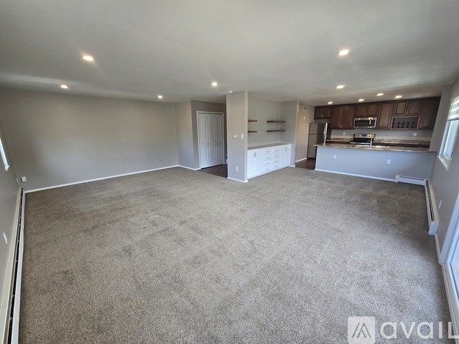 A spacious empty room with carpeted floor and white walls.