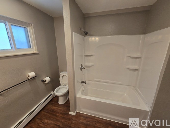 A white bathroom with a toilet, a bathtub, and a window.