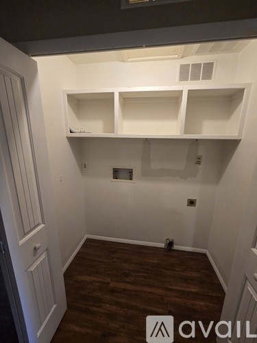 A room with white shelves and a wooden floor.
