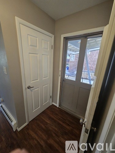 A room with a white door and a window with a view of a street.