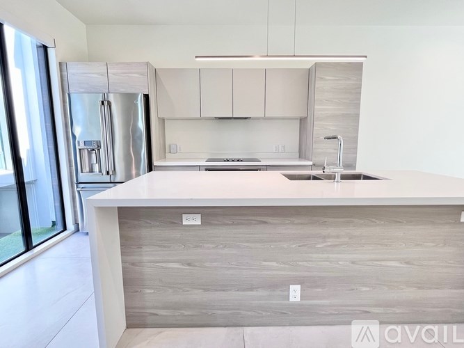 A modern kitchen with a white countertop and stainless steel appliances.