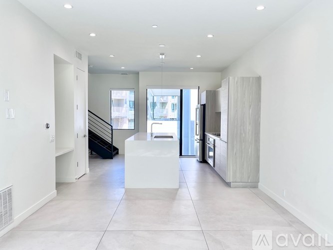 A spacious, well-lit room with a staircase and a large window.