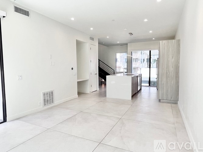 A spacious, white-walled room with a tiled floor and a staircase leading to another level.