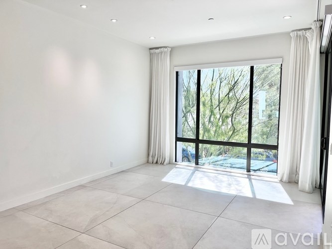 A spacious room with a large window and a view of trees and cars outside.