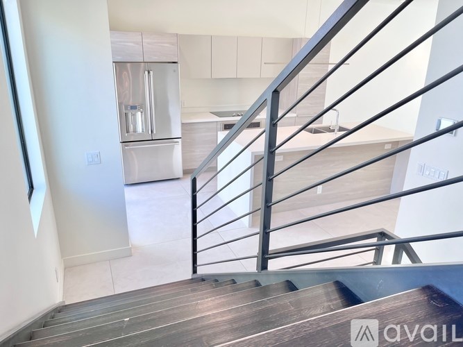 A staircase with a metal railing leads to a kitchen area.