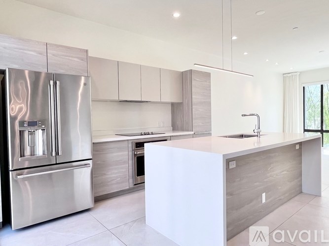 A modern kitchen with a stainless steel refrigerator and a white island.