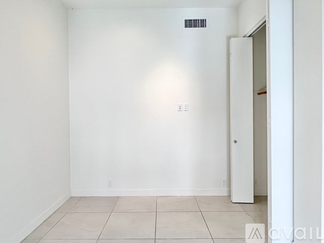 A white room with a door and a light switch on the wall.