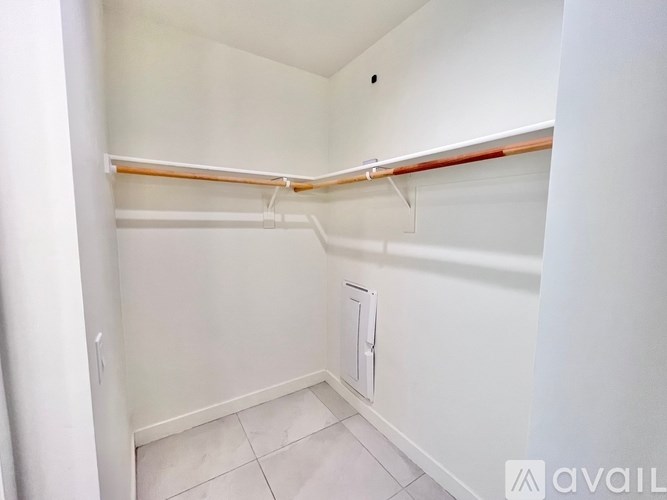 A small, empty room with a white door and a white wall.