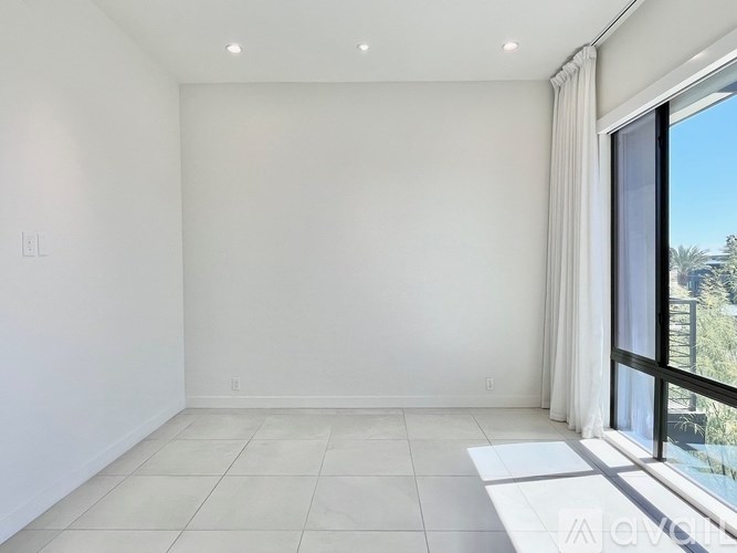 A spacious, empty room with a large window and a view of the outdoors.