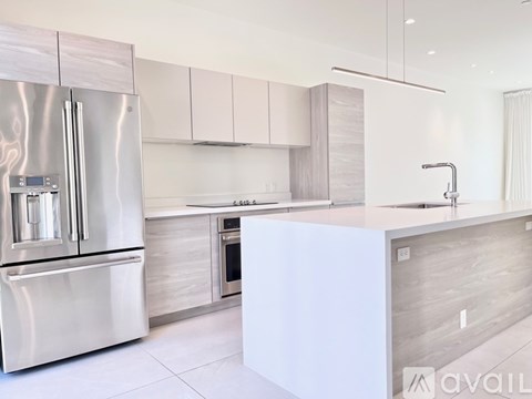 A modern kitchen with a stainless steel refrigerator and a white island.