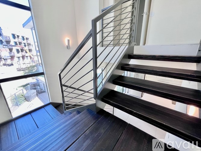 A staircase with a metal railing and wooden steps leading to a balcony with a view of a building.
