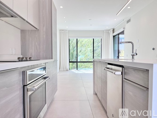 A modern kitchen with stainless steel appliances and a view of greenery outside.