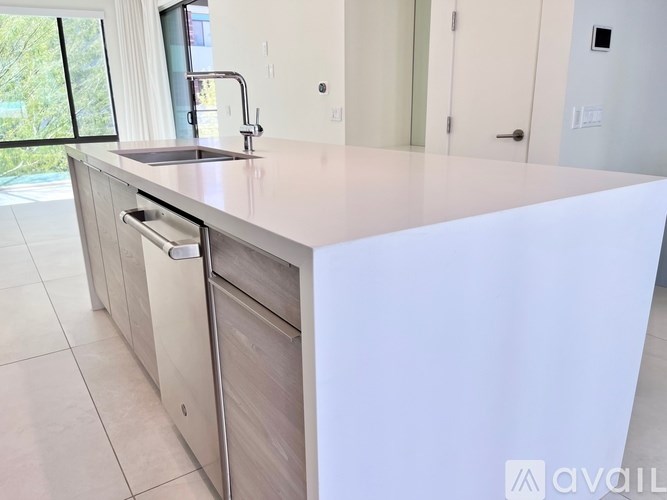 A modern kitchen with a white countertop and stainless steel appliances.