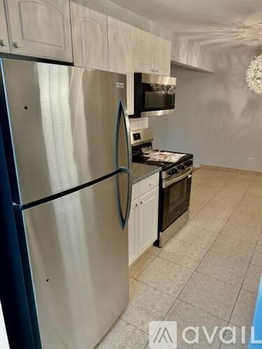 A kitchen with a stainless steel refrigerator and black appliances.