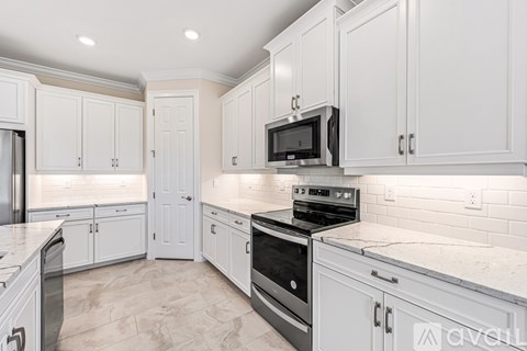 A kitchen with white cabinets and a black microwave.