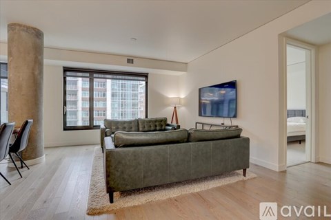 A living room with a green couch and a television on the wall.