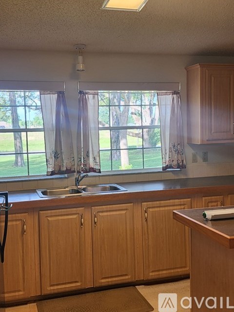 A kitchen with wooden cabinets and a window overlooking a lawn.