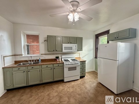 A kitchen with a white refrigerator and green cabinets.