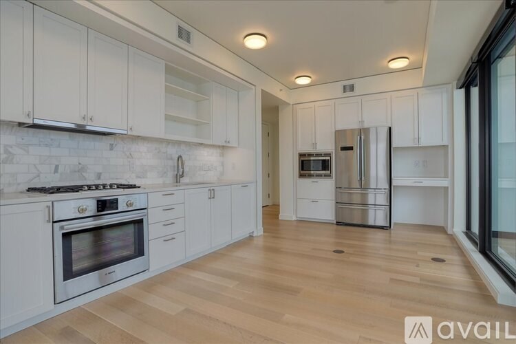 A modern kitchen with white cabinets and wooden floors.