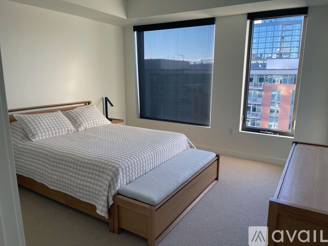 A bedroom with a large bed and a window overlooking a cityscape.