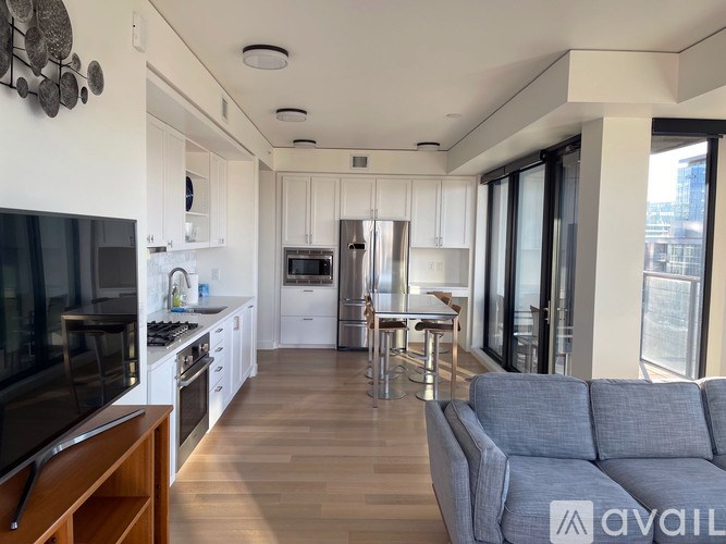 A modern kitchen with a grey sofa in the foreground.